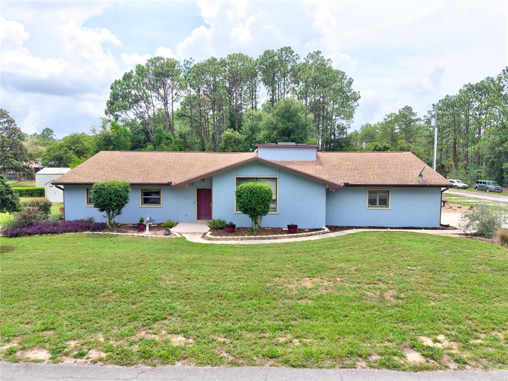 A single-story blue house with a brown shingled roof and a front lawn — 10848 N DRAGONIS DRIVE, DUNNELLON, FL