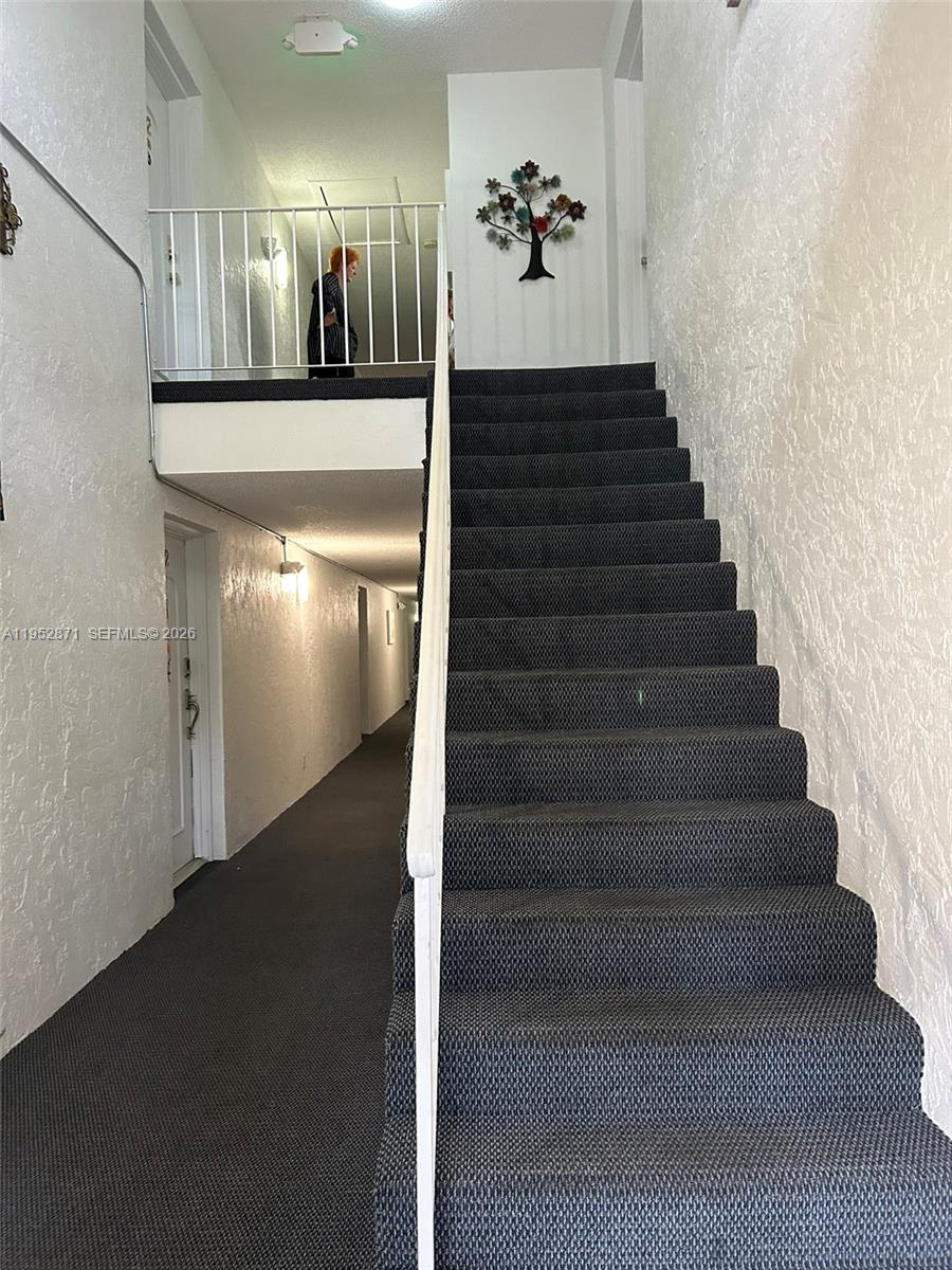 A carpeted staircase leads to an upper landing in a hallway with white textured walls — 5640 SW 3rd Pl # 212, Margate FL 33068, MARGATE, FL