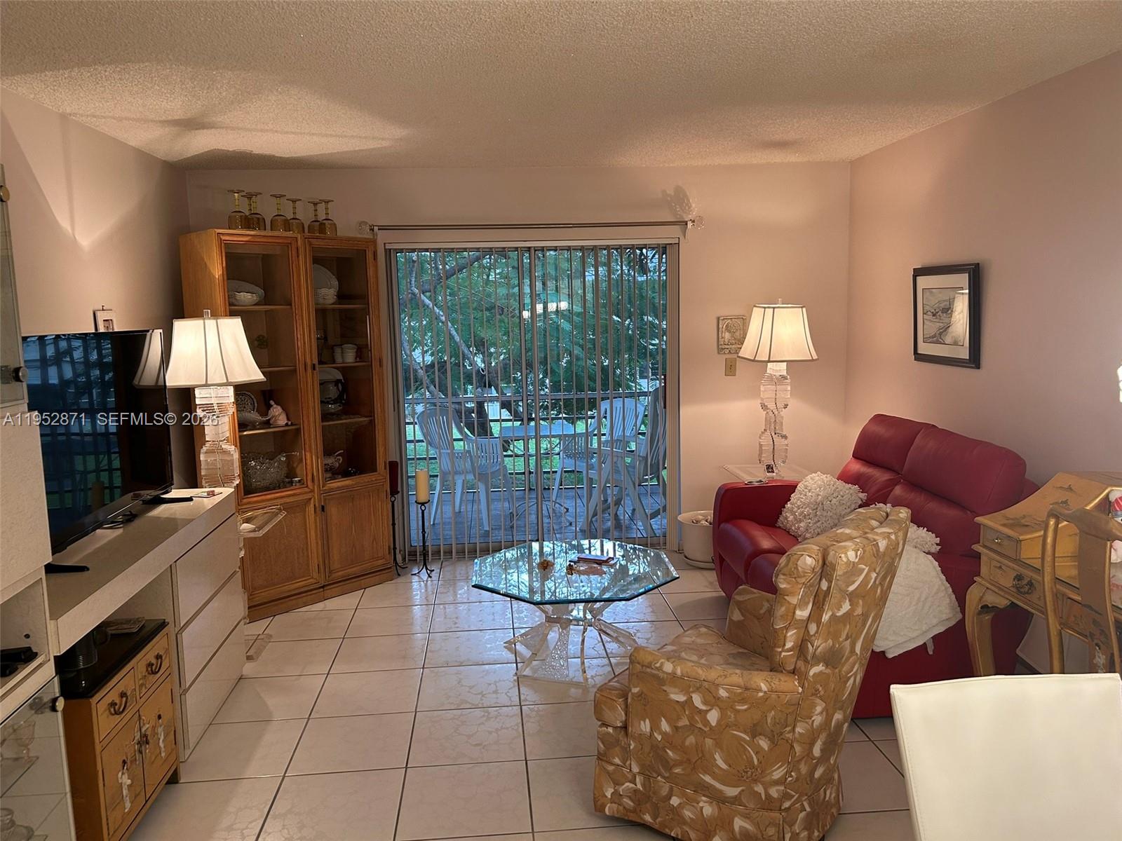 A living room features tile flooring, a red sofa, a patterned armchair, and a glass-topped table — 5640 SW 3rd Pl # 212, Margate FL 33068, MARGATE, FL