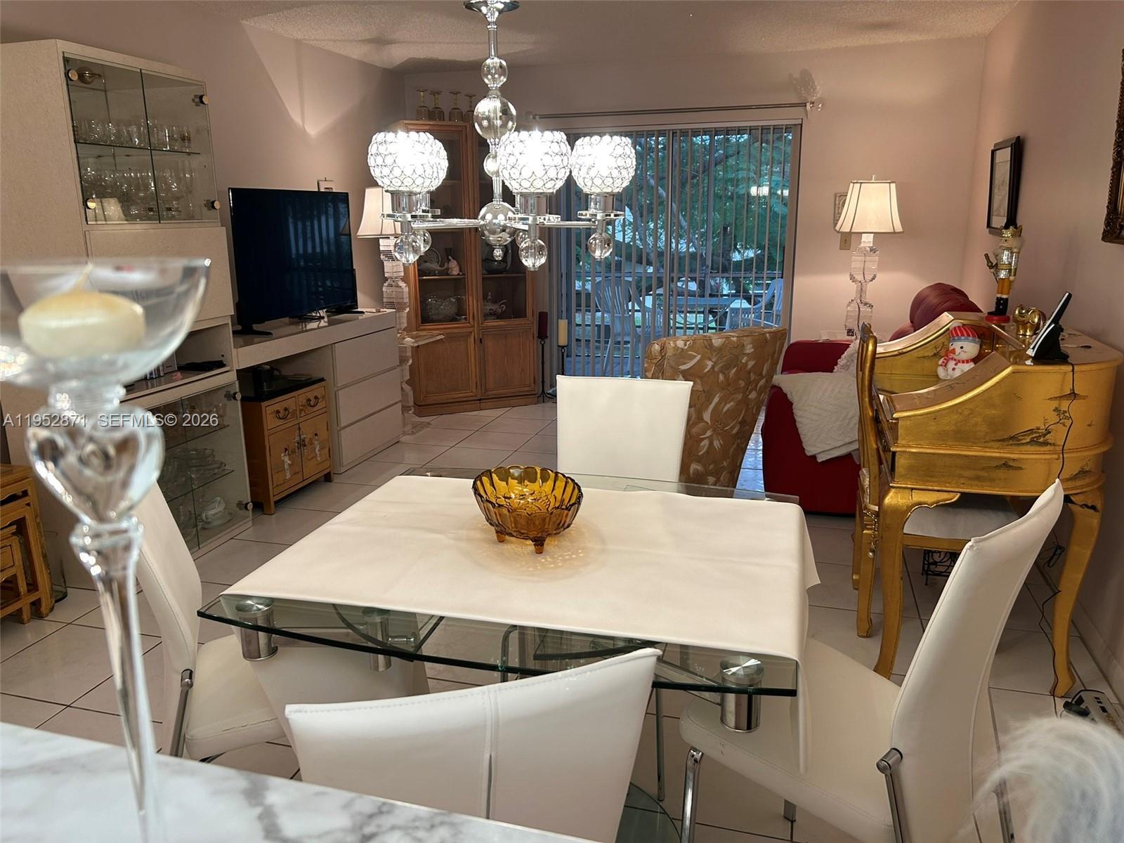 A dining area features a glass table, white chairs, a crystal chandelier, and gold furniture — 5640 SW 3rd Pl # 212, Margate FL 33068, MARGATE, FL