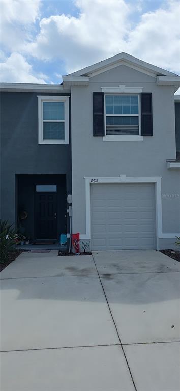 The exterior of a two-story townhouse features a gray facade, a garage, and a front entrance — 32926 KALOKO ROAD, WESLEY CHAPEL, FL