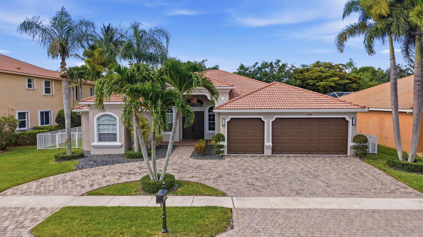 A single-story house with a tiled roof, brown garage doors, and a paved driveway — 9746 Campi Drive, Lake Worth FL 33467, LAKE WORTH, FL