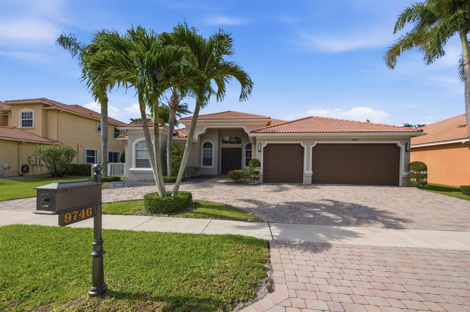 A single-story house with a tiled roof, a paved driveway, and palm trees in front — 9746 Campi Drive, Lake Worth FL 33467, LAKE WORTH, FL