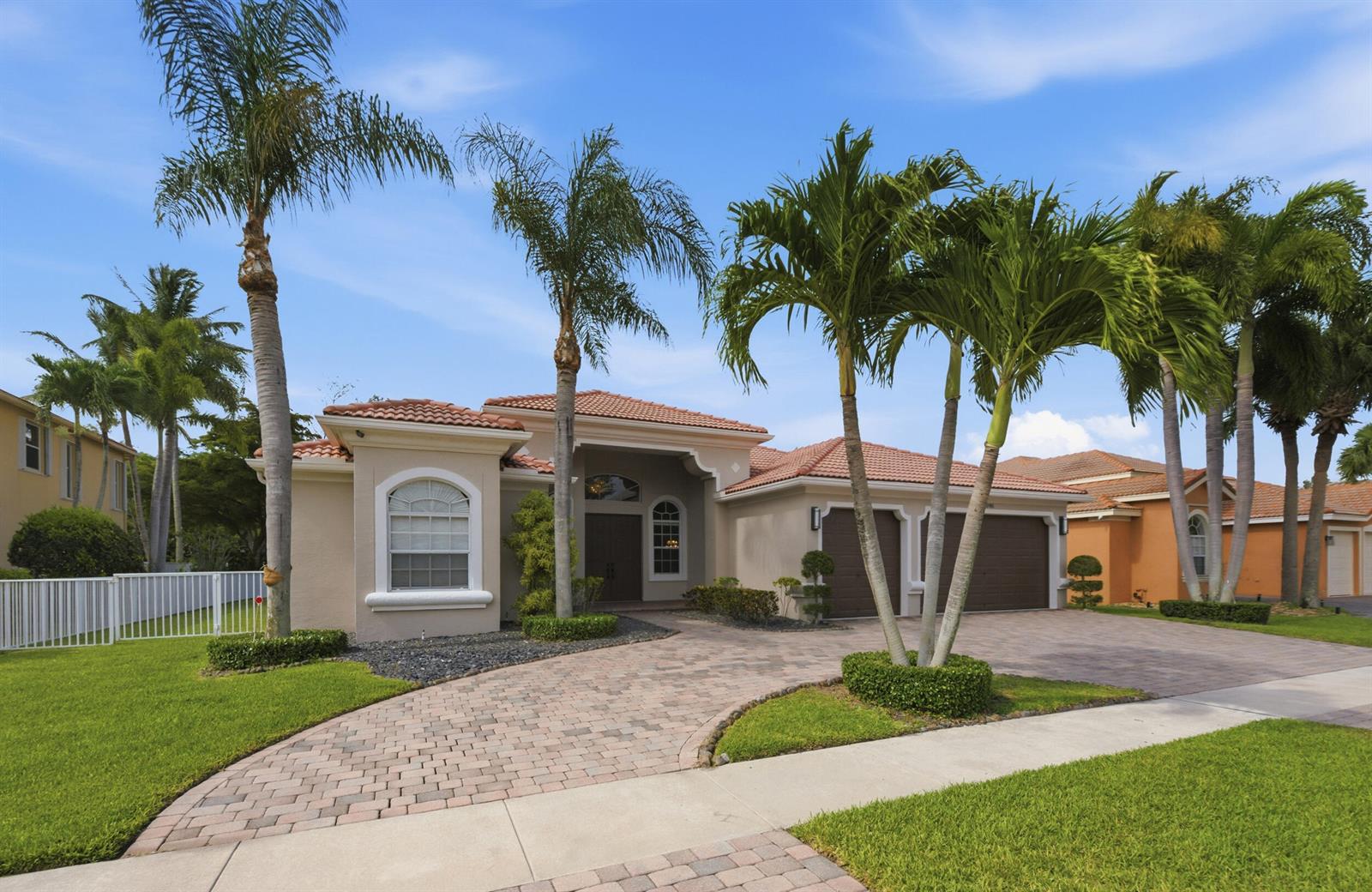 A single-story house with a tiled roof, paver driveway, and several palm trees in front — 9746 Campi Drive, Lake Worth FL 33467, LAKE WORTH, FL