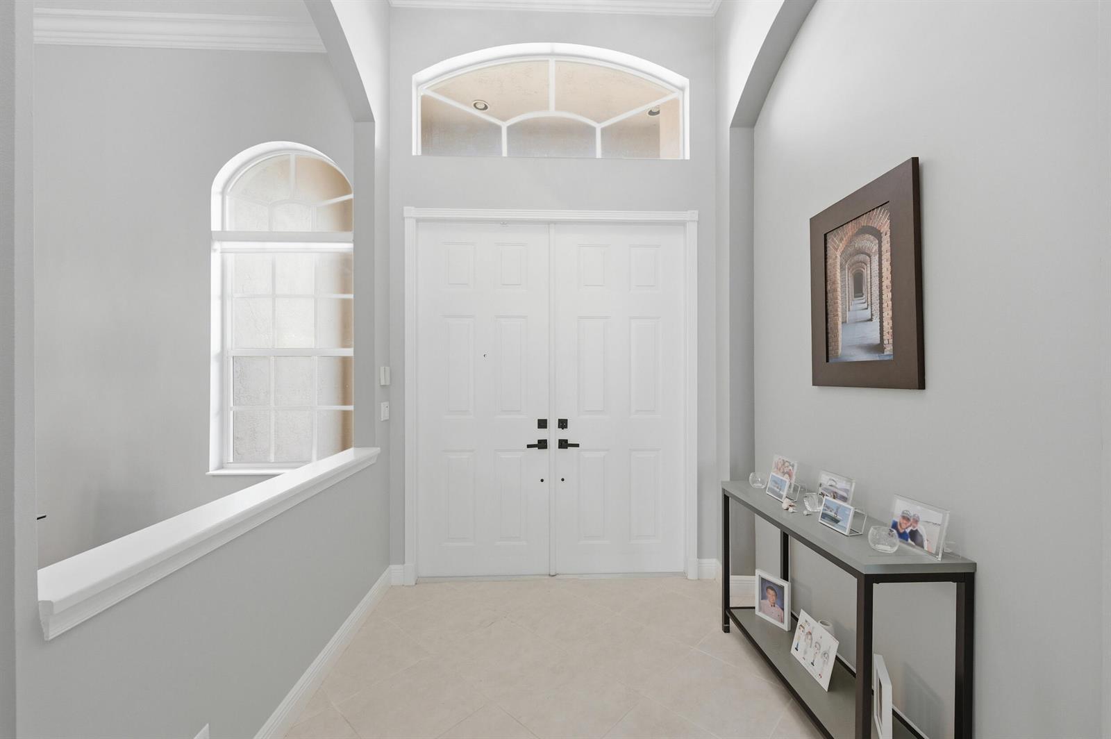 A bright entryway features white double doors, a transom window, and a metal console table — 9746 Campi Drive, Lake Worth FL 33467, LAKE WORTH, FL