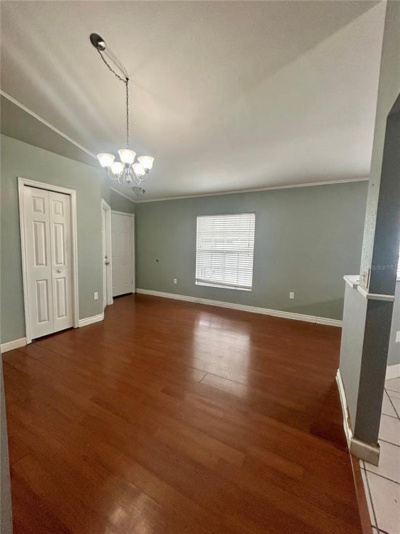 An empty room with hardwood floors, light green walls, a chandelier, and two white doors — 622 CRYSTALS BOULEVARD, WINTER HAVEN, FL