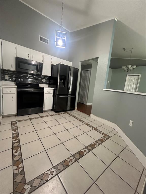 A kitchen features white cabinets, black appliances, and a tiled floor with a decorative border — 622 CRYSTALS BOULEVARD, WINTER HAVEN, FL