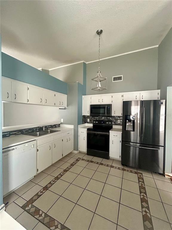 A kitchen features white cabinets, stainless steel appliances, and a tiled floor with decorative borders — 622 CRYSTALS BOULEVARD, WINTER HAVEN, FL
