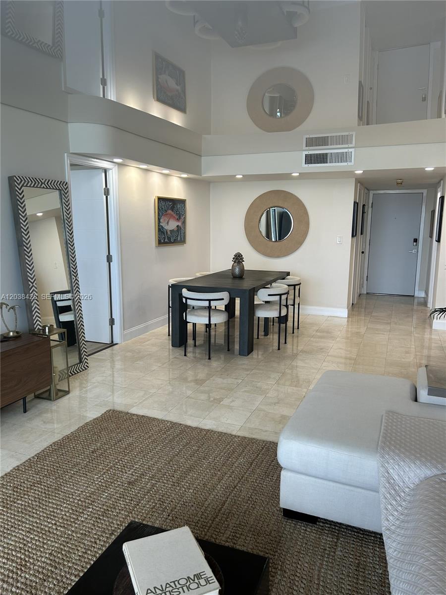 A dining area with a dark table and chairs sits in a room with high ceilings — 1904 S Ocean Dr # 1807, Hallandale Beach FL 33009, HALLANDALE BEACH, FL