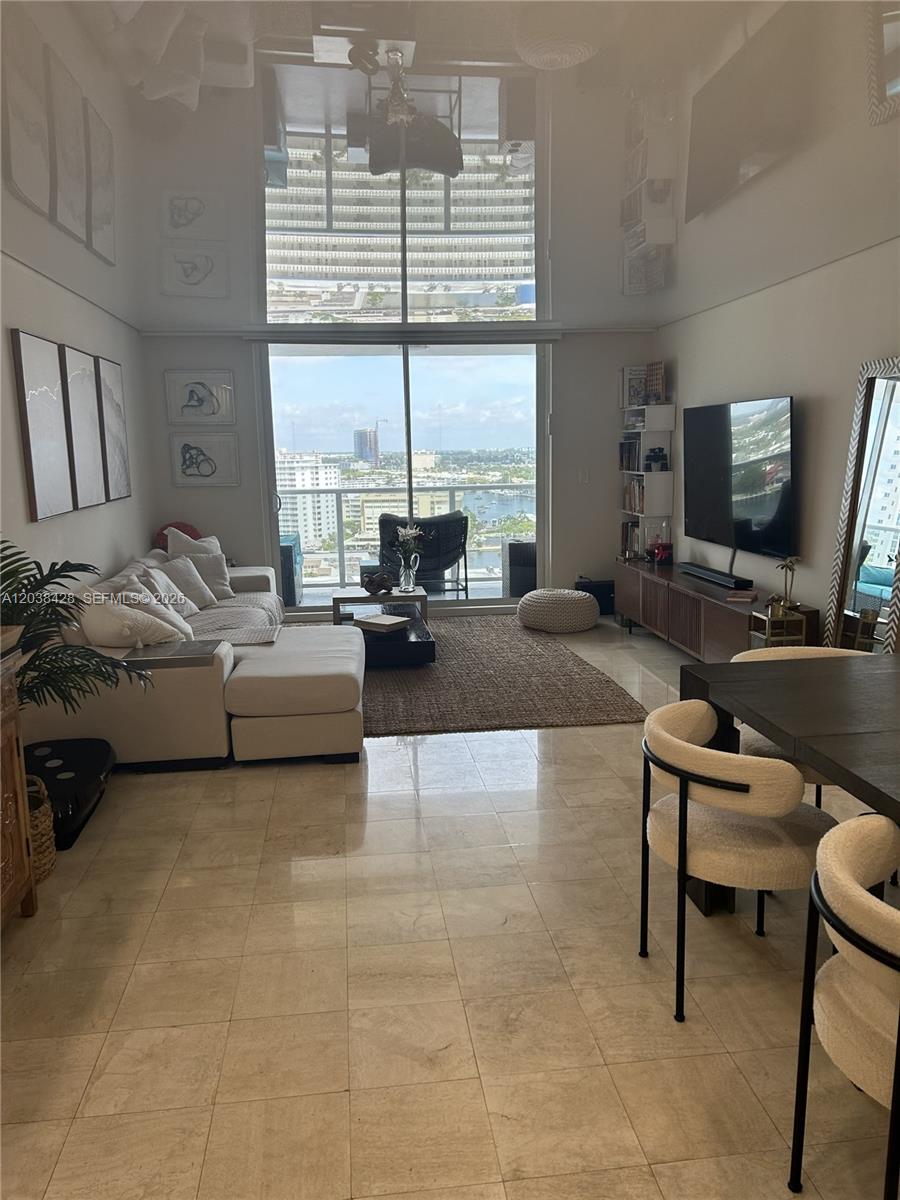 A living room features a sectional sofa, dining area, and floor-to-ceiling windows with city views — 1904 S Ocean Dr # 1807, Hallandale Beach FL 33009, HALLANDALE BEACH, FL
