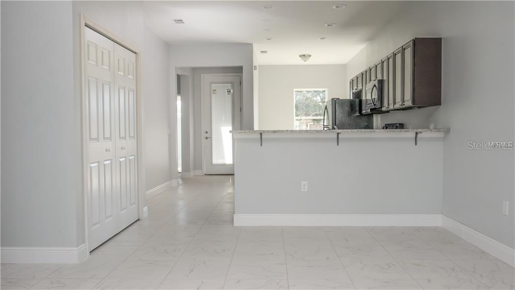 A kitchen with a breakfast bar, dark cabinets, and light tile flooring — 401 ALBATROSS COURT UNIT B, KISSIMMEE, FL