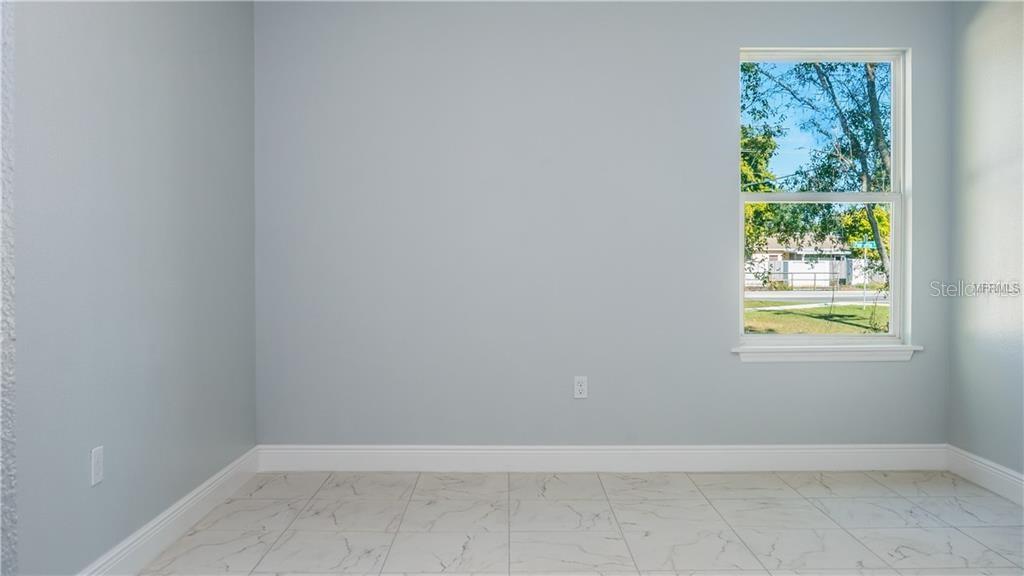 An empty room with light blue walls, white tile flooring, and a single window — 401 ALBATROSS COURT UNIT B, KISSIMMEE, FL