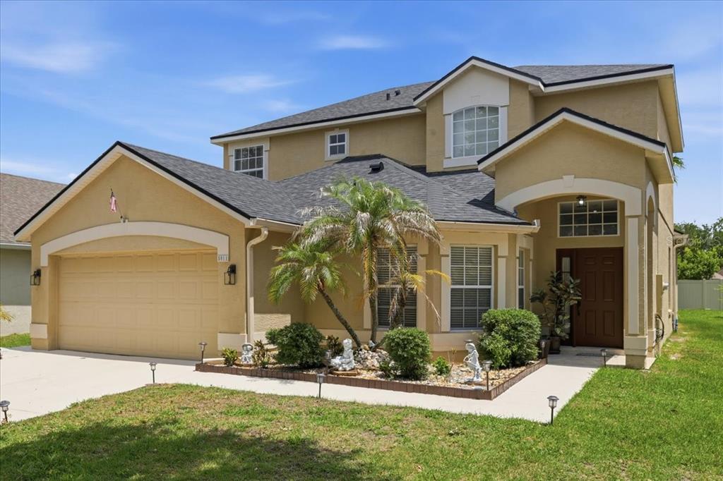 A two-story suburban house with a tan stucco exterior, a two-car garage, and a palm tree — 5011 CORTO DRIVE, ORLANDO, FL