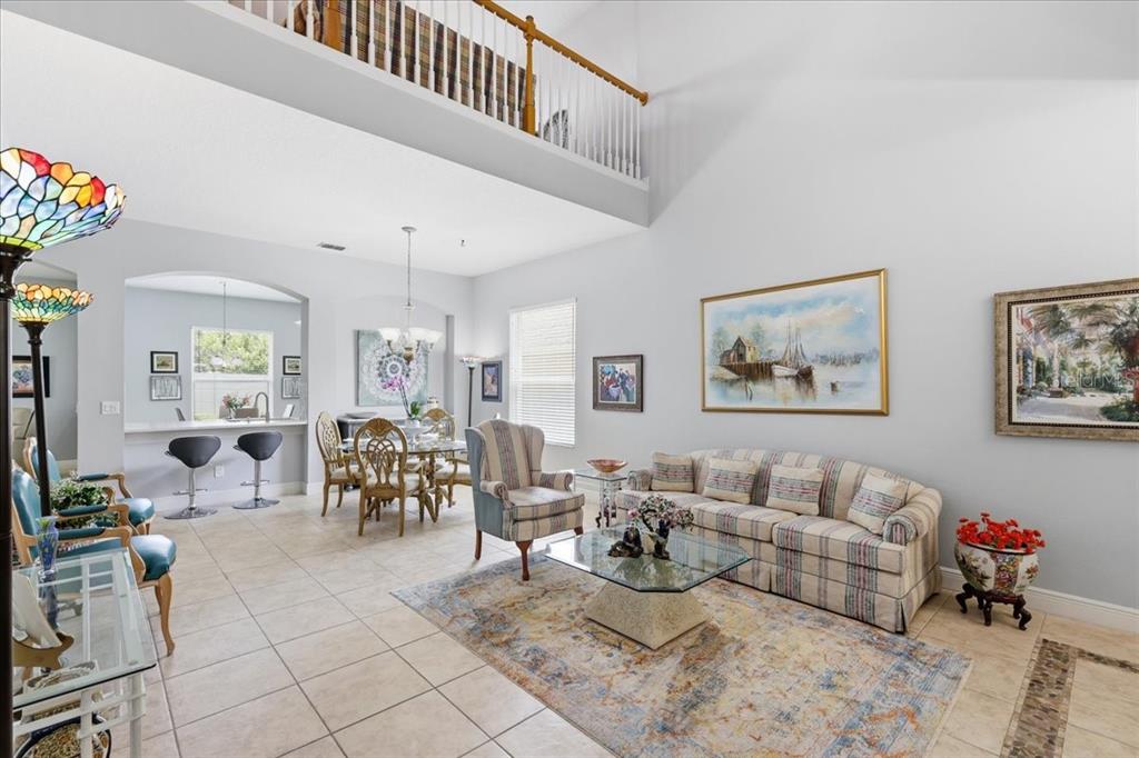 A living and dining area with high ceilings, tile floors, and a loft overlook — 5011 CORTO DRIVE, ORLANDO, FL