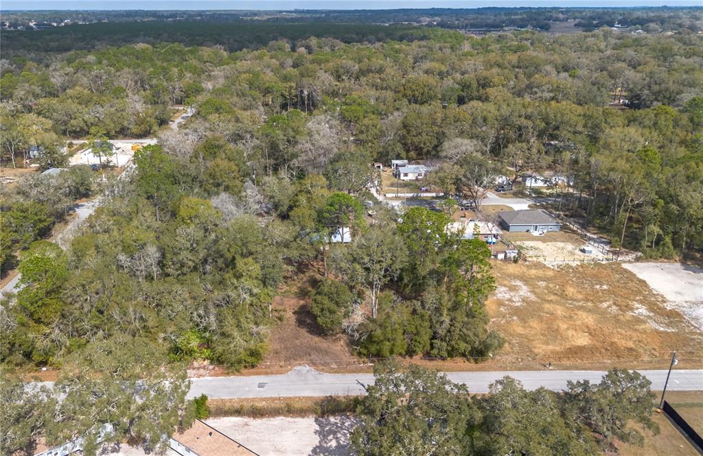 An aerial view shows a wooded residential lot situated along a paved road — NW 13TH STREET, OCALA, FL