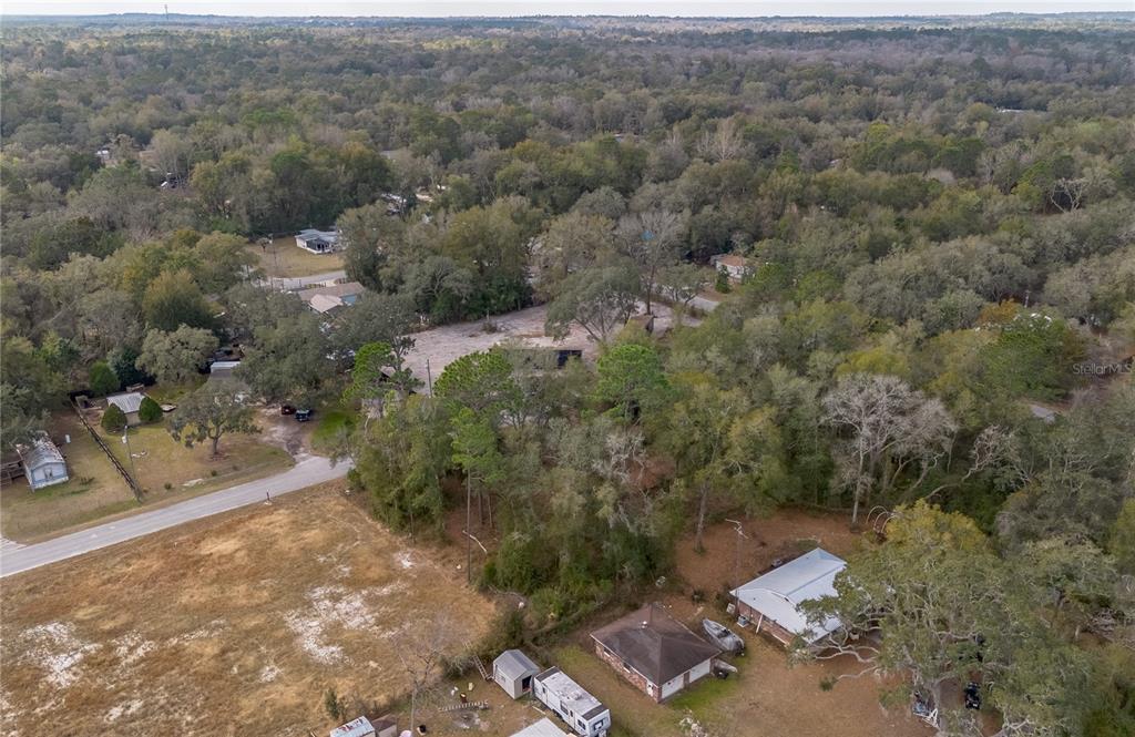 An aerial view shows a rural residential area with scattered houses, trees, and dirt roads — NW 13TH STREET, OCALA, FL