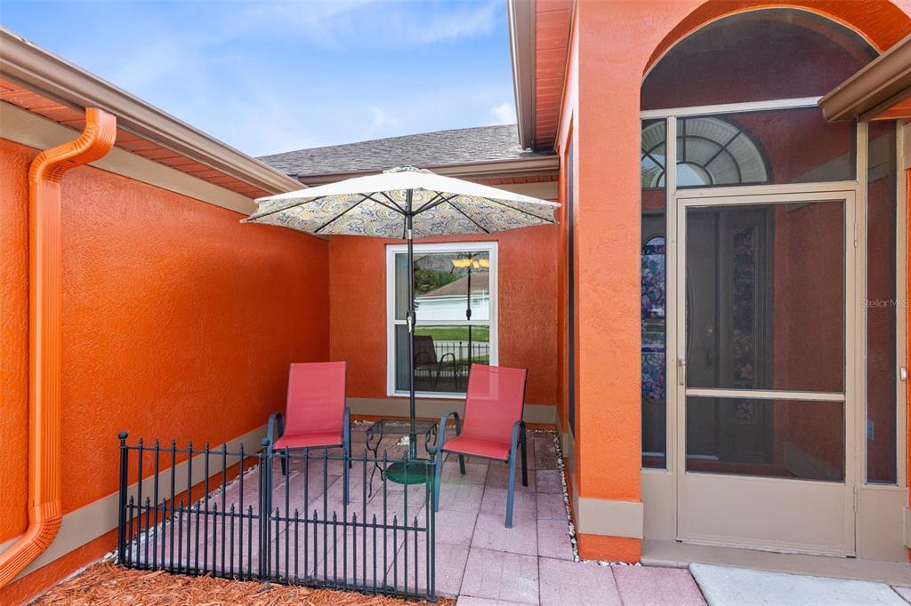 A small patio with two red chairs, a table, and an umbrella sits outside — 949 ROSINIA COURT, ORLANDO, FL