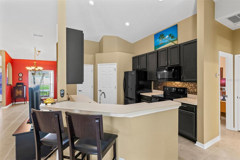A kitchen features dark cabinets, black appliances, a breakfast bar, and tan walls — 949 ROSINIA COURT, ORLANDO, FL