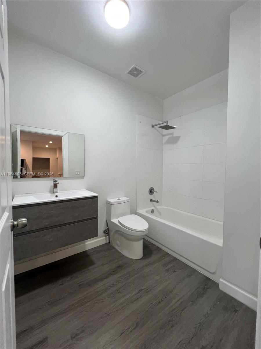 A modern bathroom features a floating vanity, a toilet, and a shower-tub combination — 2311 NW 22nd Ave # 405, Miami FL 33142, MIAMI, FL