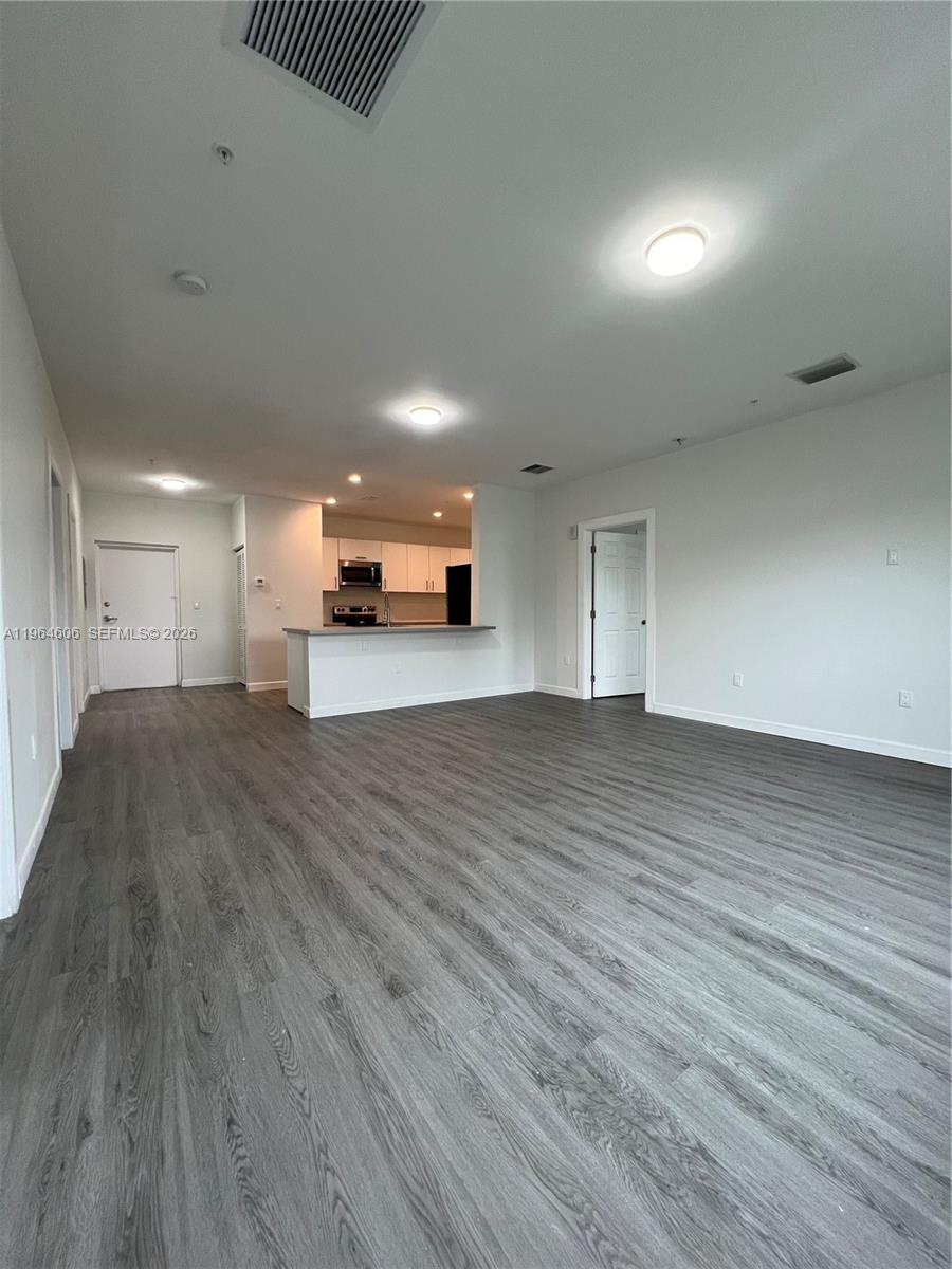 An open-concept living area features gray wood-look flooring and a kitchen with white cabinets — 2311 NW 22nd Ave # 405, Miami FL 33142, MIAMI, FL