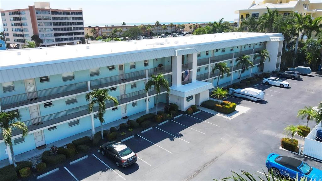 An aerial view shows a light blue three-story apartment building with a parking lot — 9200 MIDNIGHT PASS ROAD UNIT 24, SARASOTA, FL
