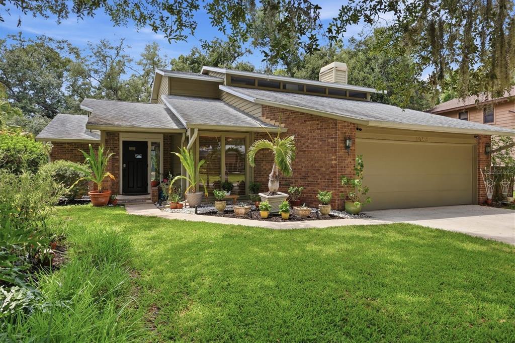 A single-story brick house with a large garage, shingled roof, and landscaped front yard — 1063 GREYSTONE LANE, SARASOTA, FL