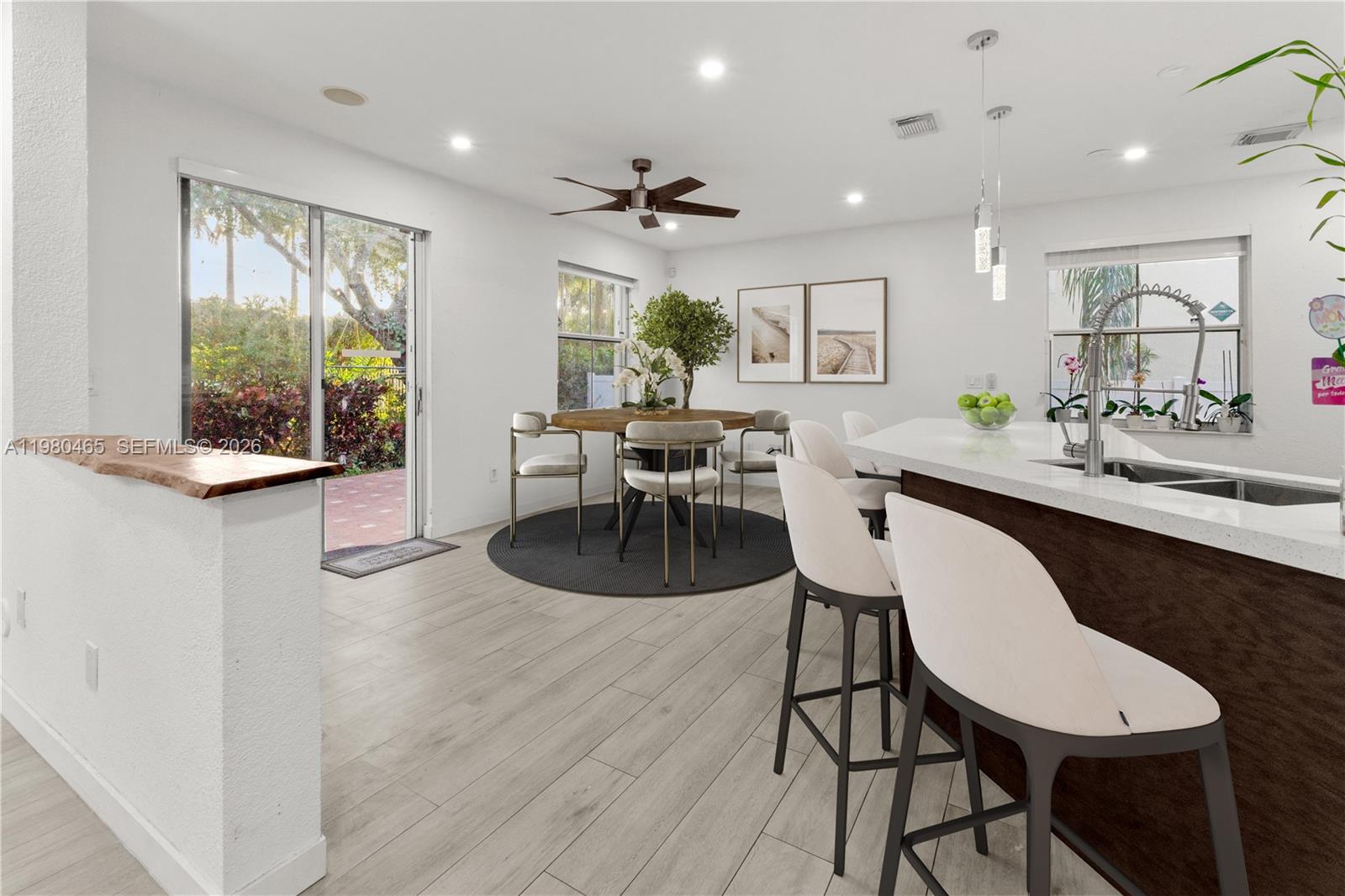 A bright kitchen and dining area features white walls, light wood floors, and bar seating — 17130 SW 36th Ct, Miramar FL 33027, MIRAMAR, FL