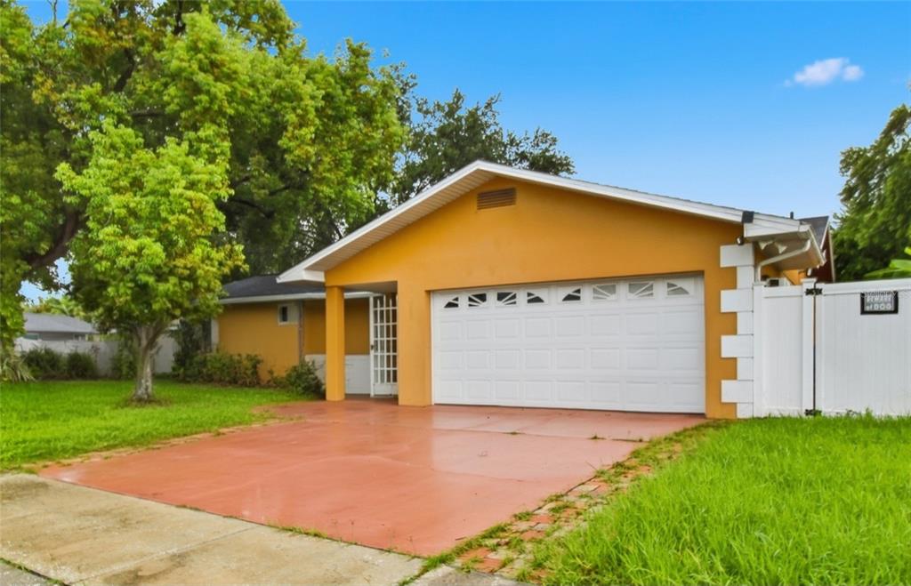 A yellow house with a white garage door and a red concrete driveway — 11351 130TH AVENUE, LARGO, FL