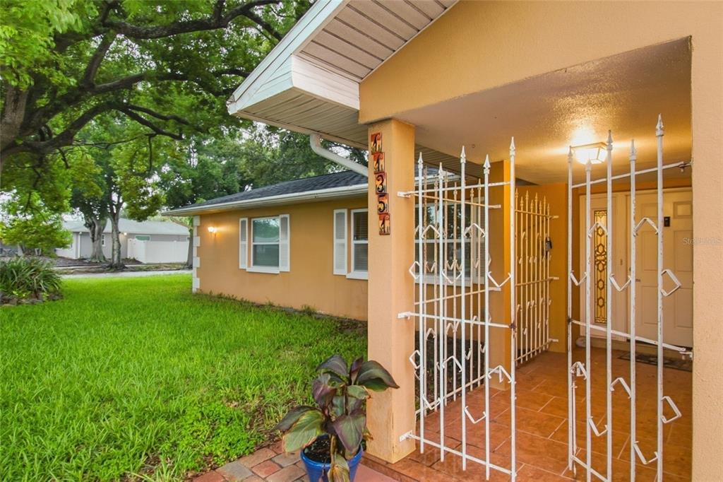 A side view of a house exterior featuring a tiled porch with a white metal gate — 11351 130TH AVENUE, LARGO, FL