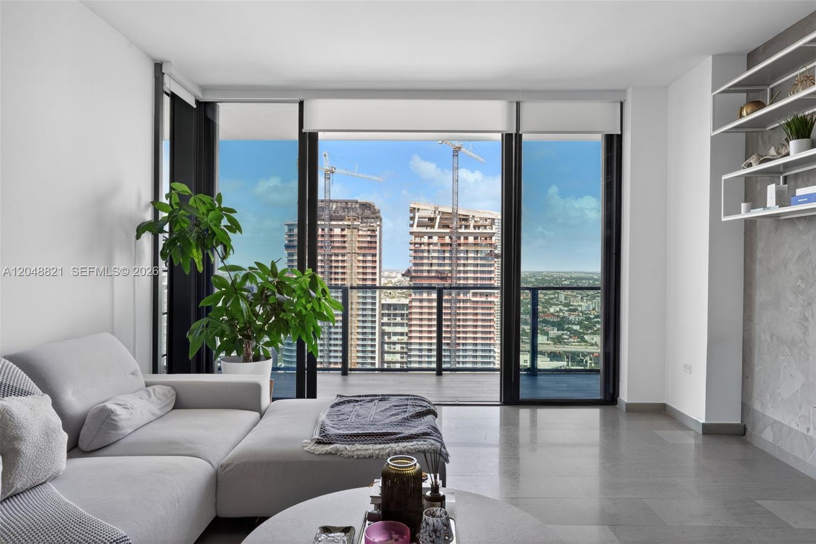 A living room features a light gray sectional sofa, a coffee table, and floor-to-ceiling windows — 68 SE 6th St # 3710, Miami FL 33131, MIAMI, FL