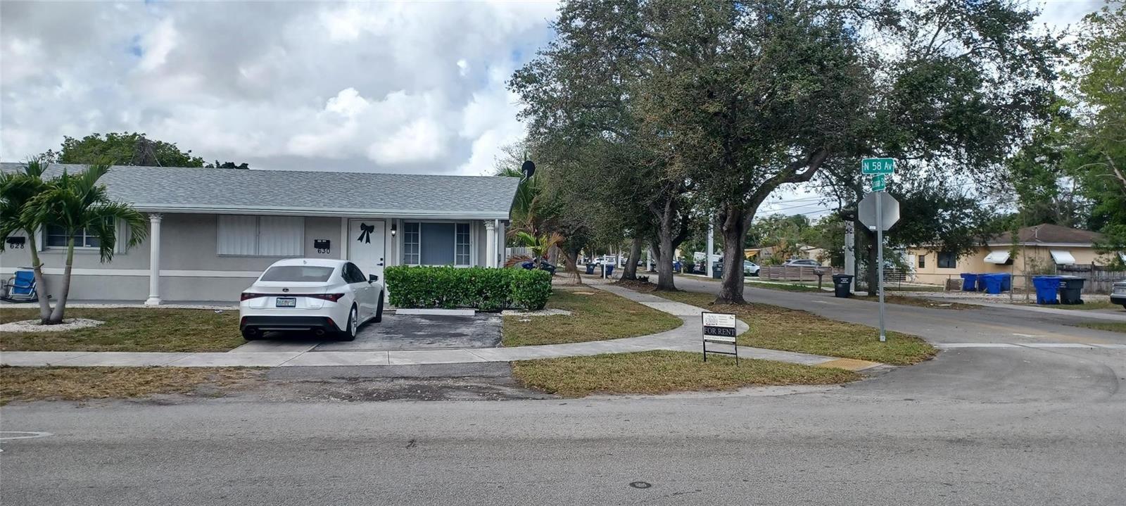 A white sedan is parked in the driveway of a single-story house with gray siding — 630 N 58th Avenue, Hollywood FL 33021, HOLLYWOOD, FL