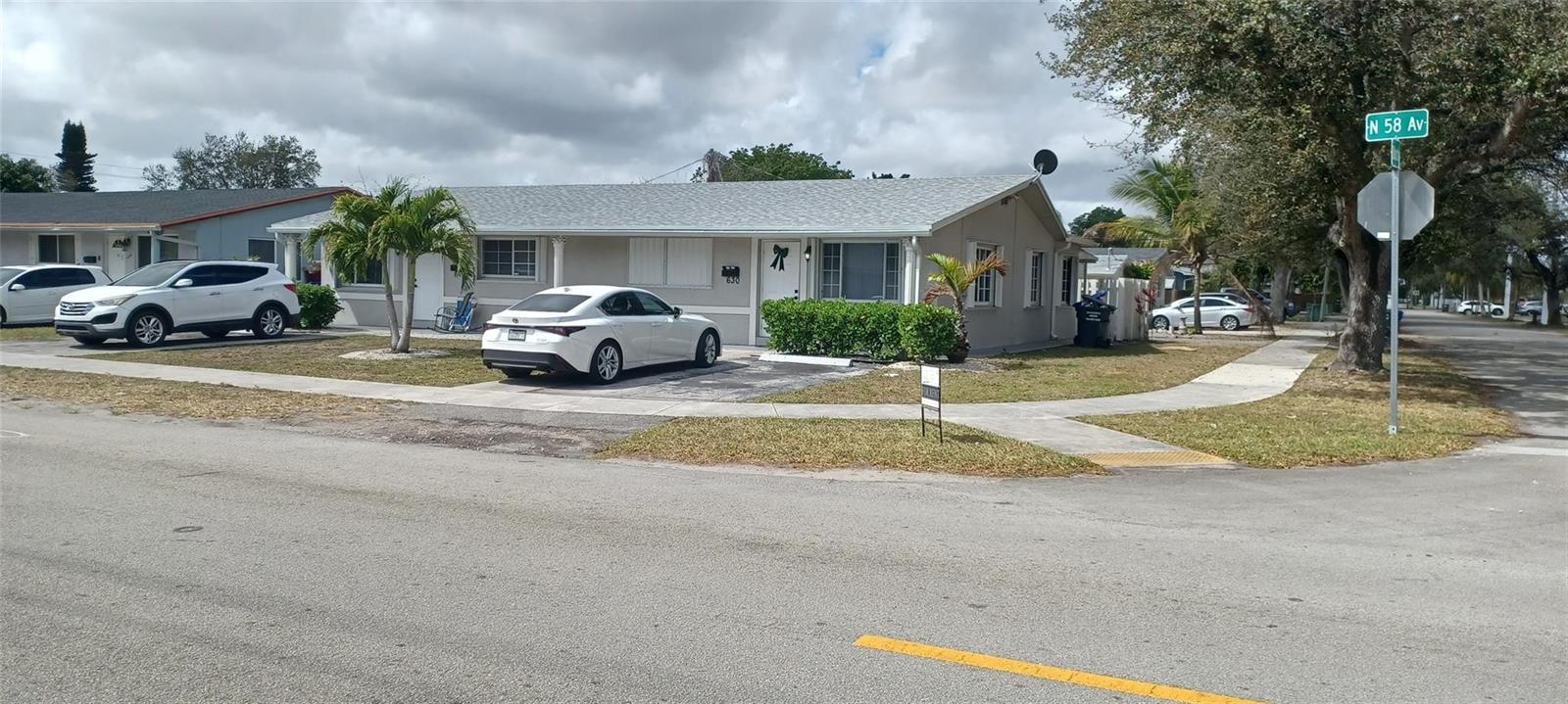 A single-story house with a white exterior, a gray roof, and a driveway with cars — 630 N 58th Avenue, Hollywood FL 33021, HOLLYWOOD, FL