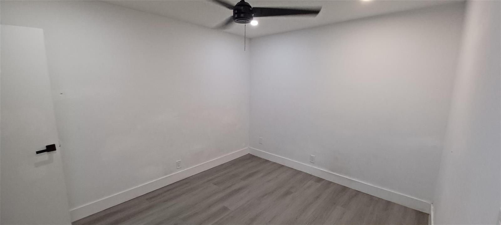 An empty bedroom features white walls, gray wood-look flooring, and a ceiling fan — 630 N 58th Avenue, Hollywood FL 33021, HOLLYWOOD, FL