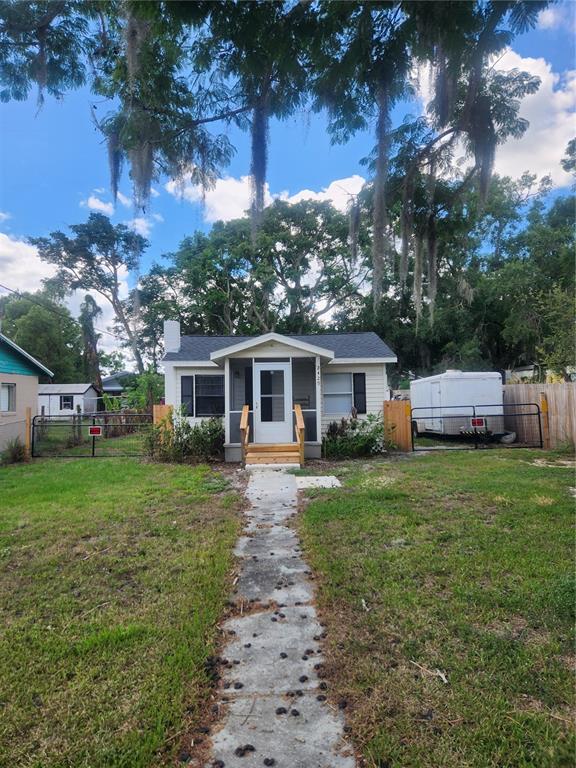 A small, light-colored house with a front porch and a concrete walkway sits under trees — 2429 LAKEVIEW STREET, LAKELAND, FL