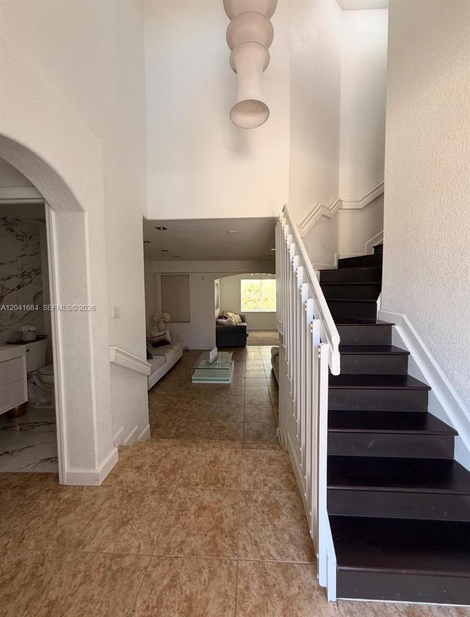 A foyer with tile flooring leads to a living area, featuring a staircase with dark treads — 10958 NW 86th Ter, Doral FL 33178, DORAL, FL