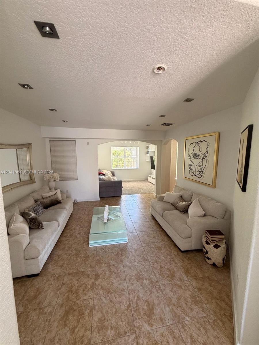 A living room features two beige sofas, a glass coffee table, and tile flooring — 10958 NW 86th Ter, Doral FL 33178, DORAL, FL