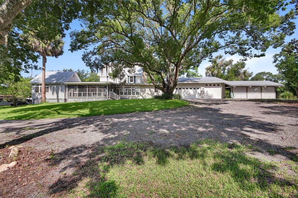 A large, light-colored house with a gravel driveway, screened porch, and mature trees — 900 E KICKLIGHTER ( 15+/- ACRES) ROAD, LAKE HELEN, FL
