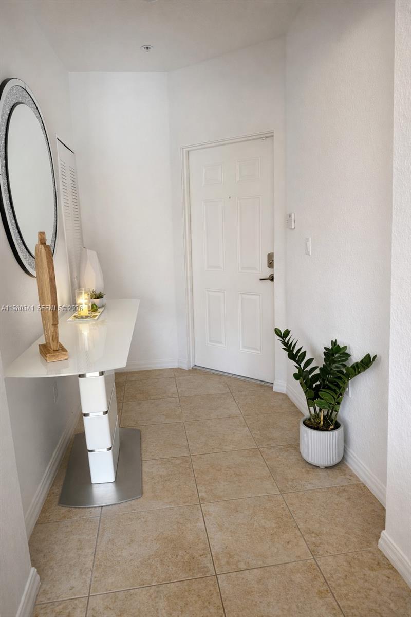 An entryway features a white console table, a round mirror, and a potted plant on tile — 8899 NW 107th Ct # 219, Doral FL 33178, DORAL, FL