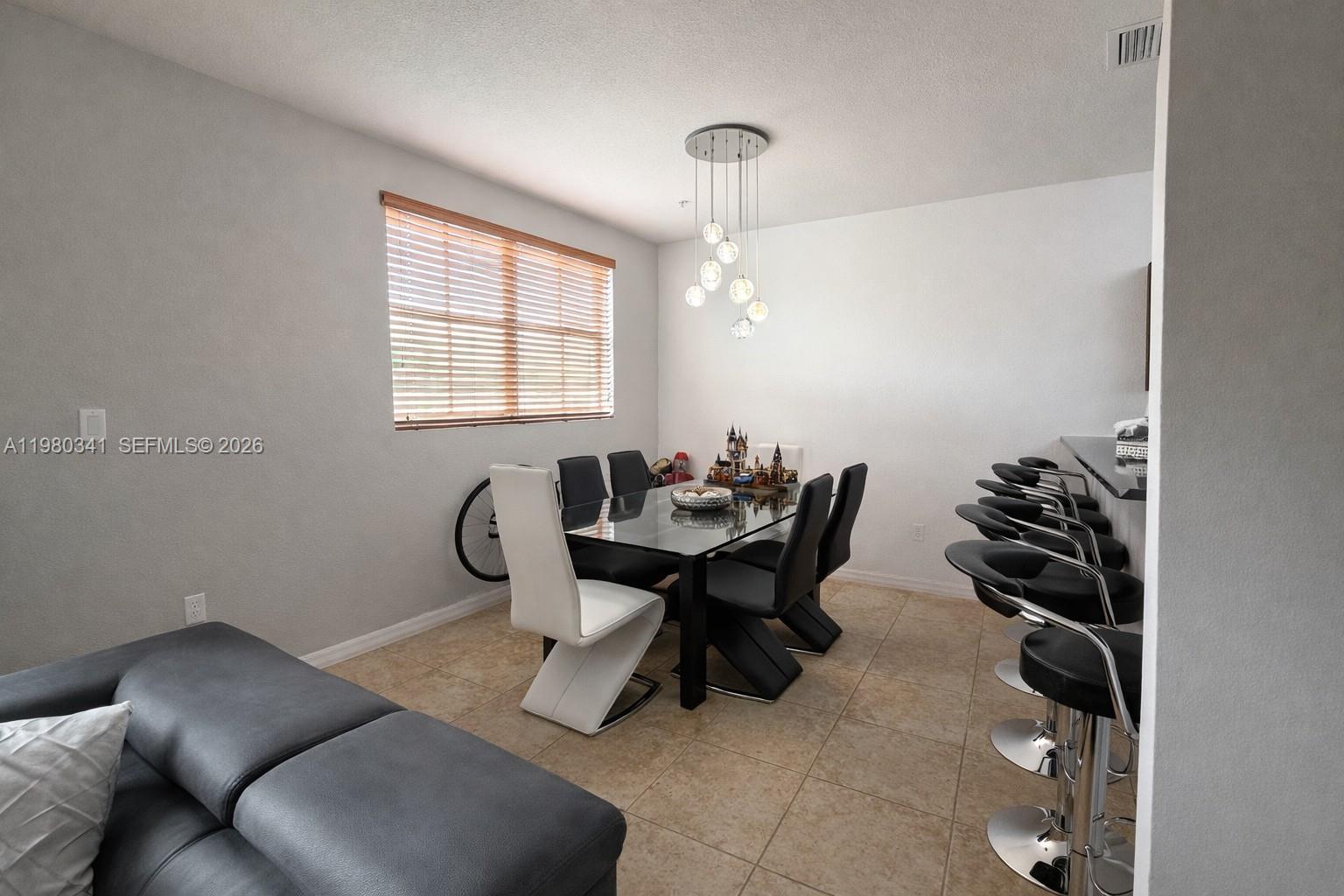 A dining area features a glass table, modern chairs, a pendant light, and bar seating — 8899 NW 107th Ct # 219, Doral FL 33178, DORAL, FL