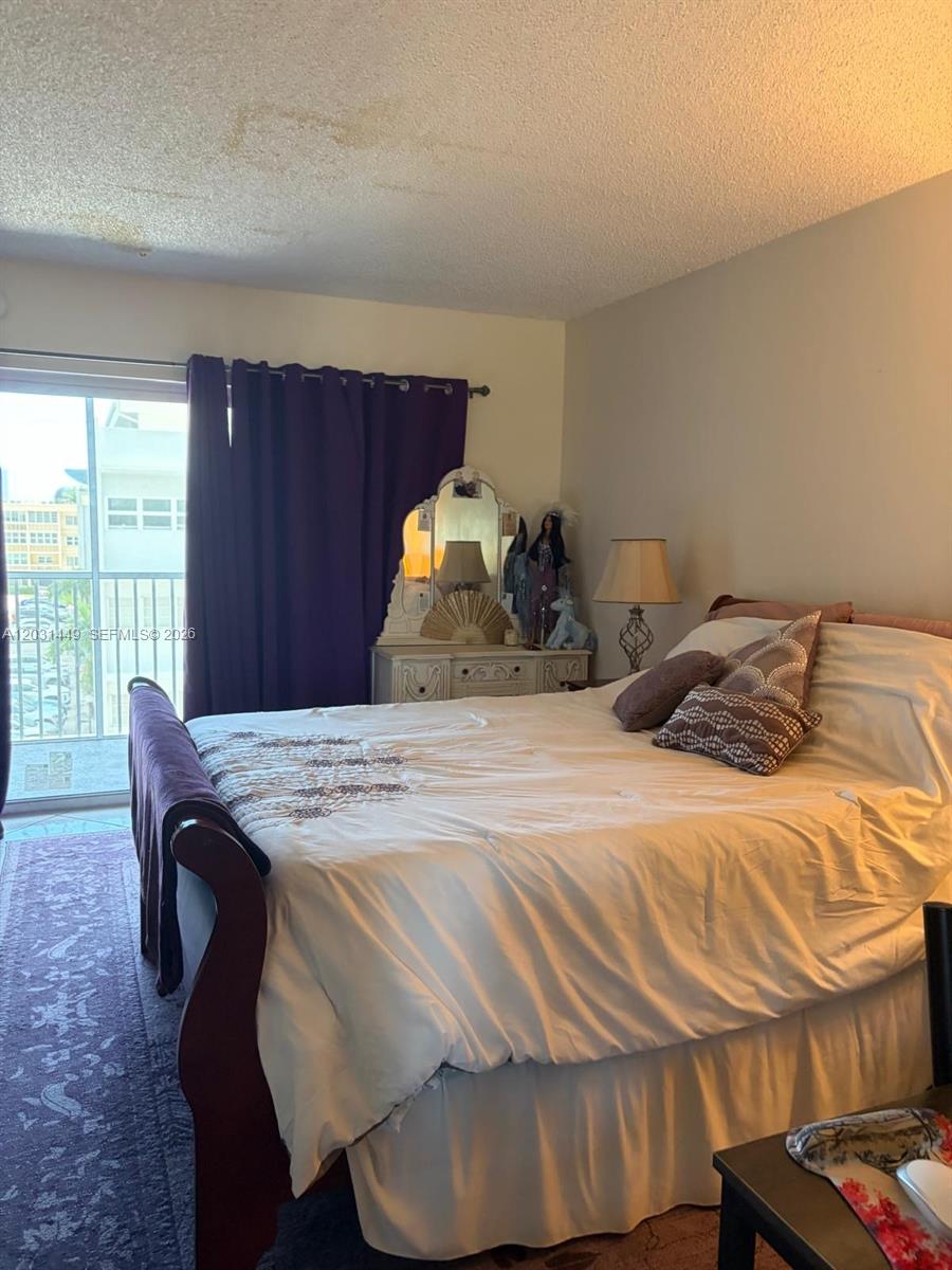 A bedroom features a bed with white bedding, a vanity with a mirror, and purple curtains — 215 SE 3rd Ave # 403A, Hallandale Beach FL 33009, HALLANDALE BEACH, FL