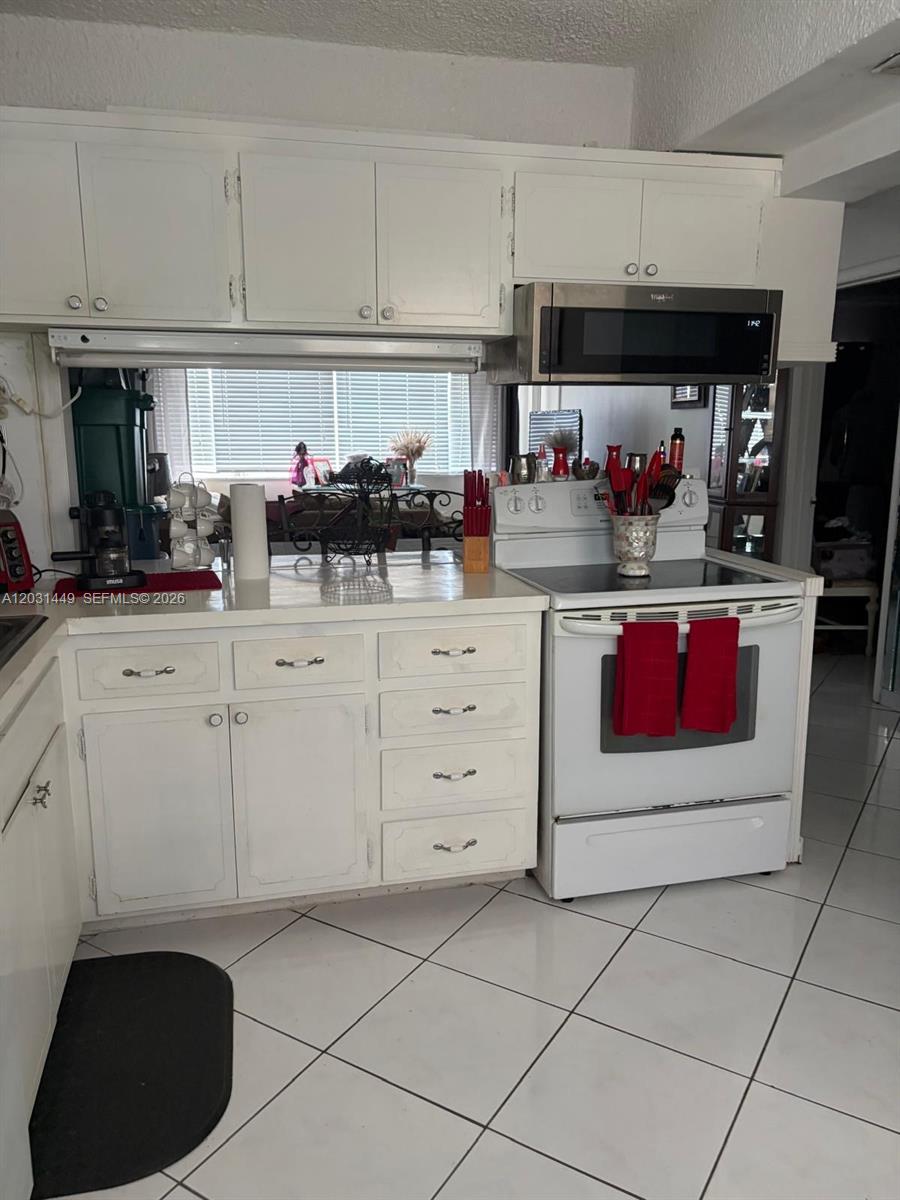 A kitchen features white cabinets, white appliances, a tiled floor, and a window above counters — 215 SE 3rd Ave # 403A, Hallandale Beach FL 33009, HALLANDALE BEACH, FL