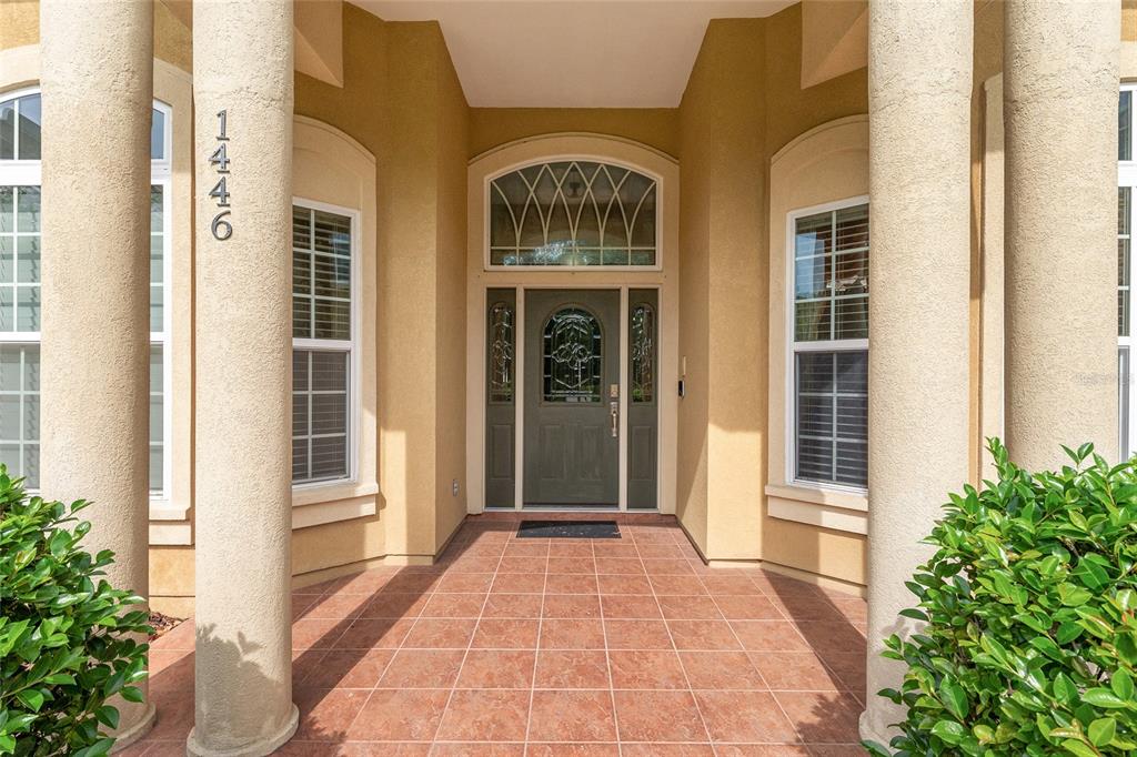 A front entryway features a tiled porch, two large columns, and a decorative glass door — 1446 SW 87TH STREET, GAINESVILLE, FL