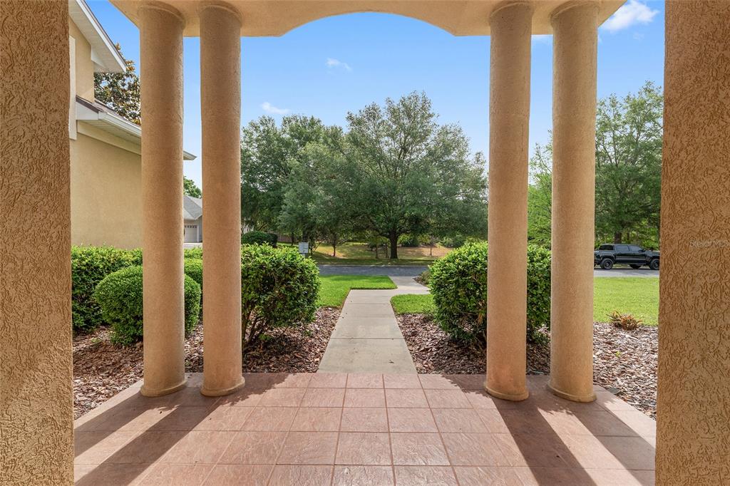 A covered entryway with four columns overlooks a walkway, green lawn, and trees — 1446 SW 87TH STREET, GAINESVILLE, FL