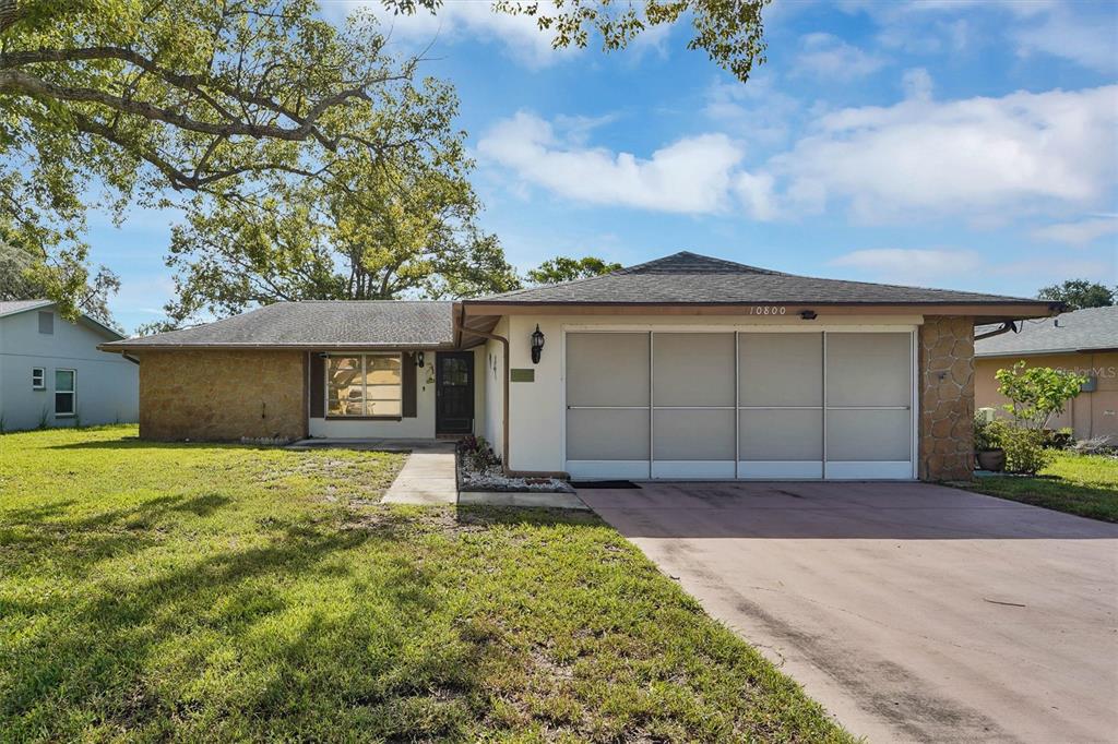 A single-story house with a stone facade, a two-car garage, and a large front lawn — 10800 LOS SANTOS DRIVE, PORT RICHEY, FL