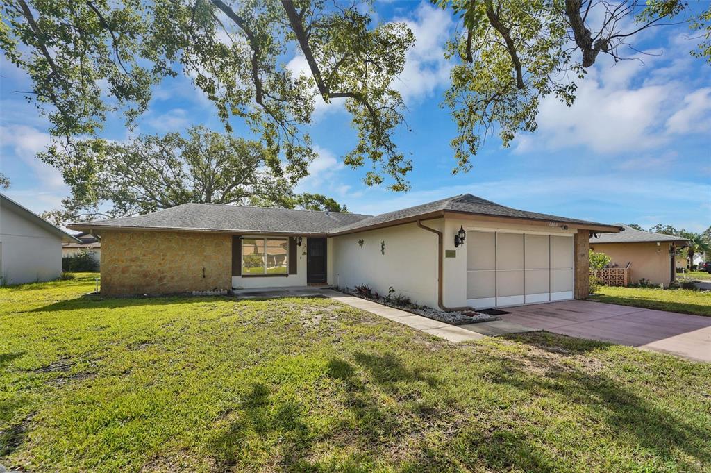 A single-story house with a stone facade, white stucco walls, and an attached garage — 10800 LOS SANTOS DRIVE, PORT RICHEY, FL