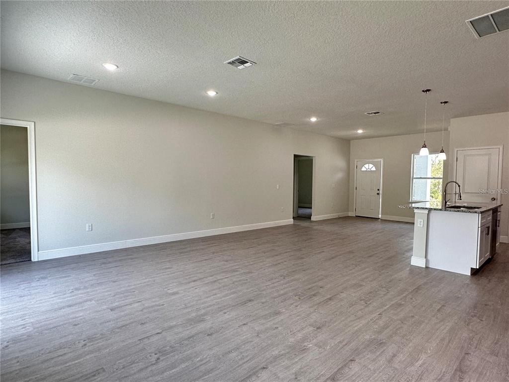An open-concept living area features light gray wood-look flooring, recessed lighting, and a kitchen island — 149 MAPLE DRIVE, POINCIANA, FL