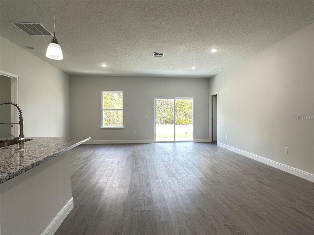A kitchen island with granite countertops overlooks a spacious living area with wood-look flooring — 149 MAPLE DRIVE, POINCIANA, FL