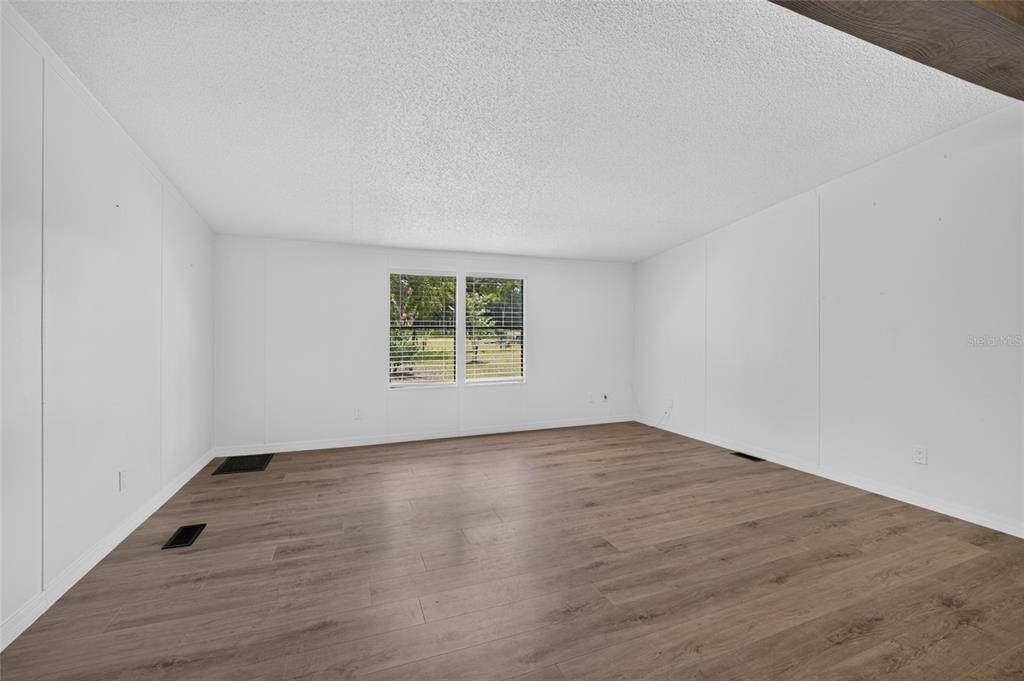 An empty room with white walls, a popcorn ceiling, and light wood-look flooring — 3353 SW 181ST COURT, DUNNELLON, FL