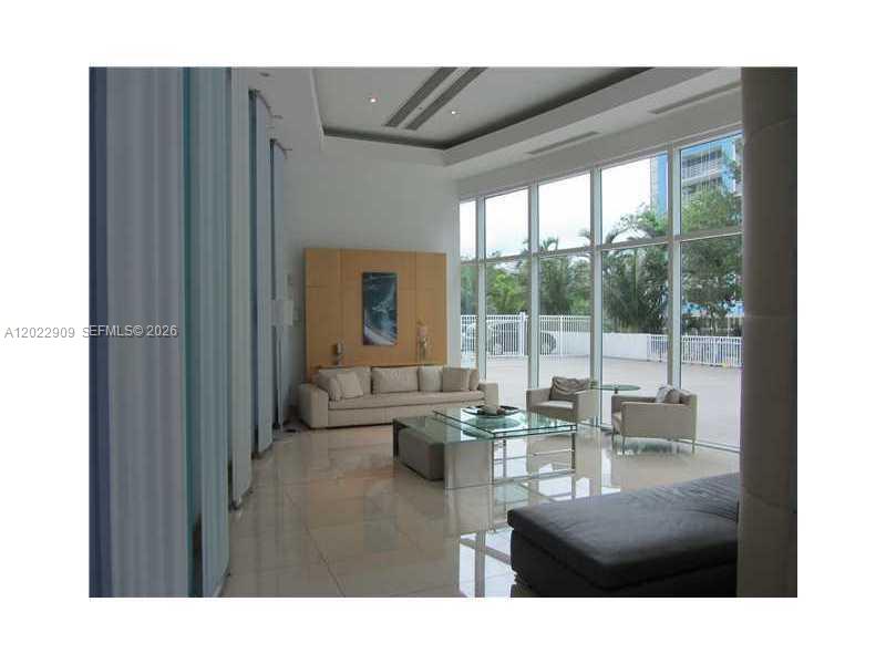 A modern living room features a beige sofa, glass coffee table, and floor-to-ceiling windows — 2101 BRICKELL # 410, Miami FL 33131, MIAMI, FL
