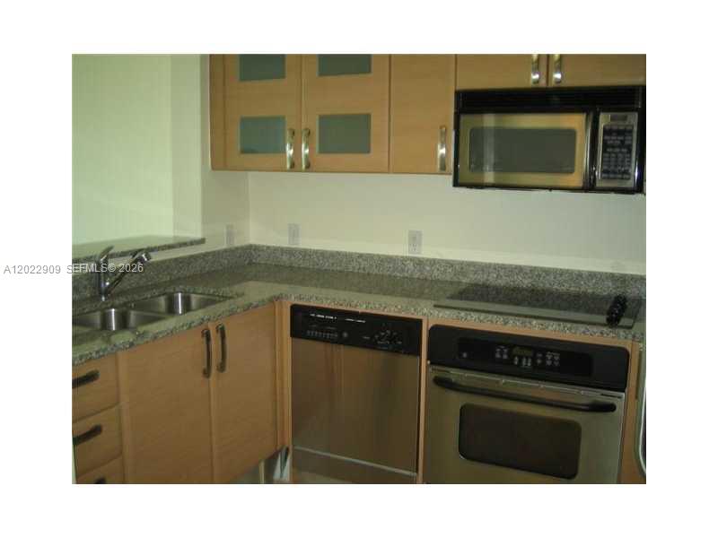 A kitchen features light wood cabinets, stainless steel appliances, and dark granite countertops — 2101 BRICKELL # 410, Miami FL 33131, MIAMI, FL